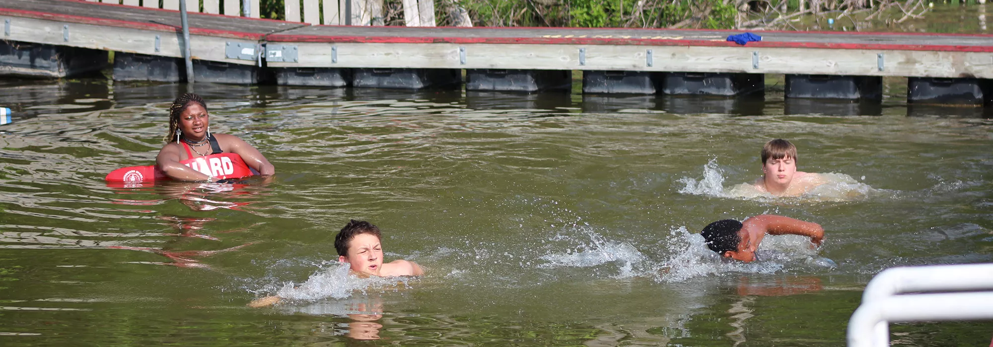 Campers swimming in the water while a lifeguard watches
